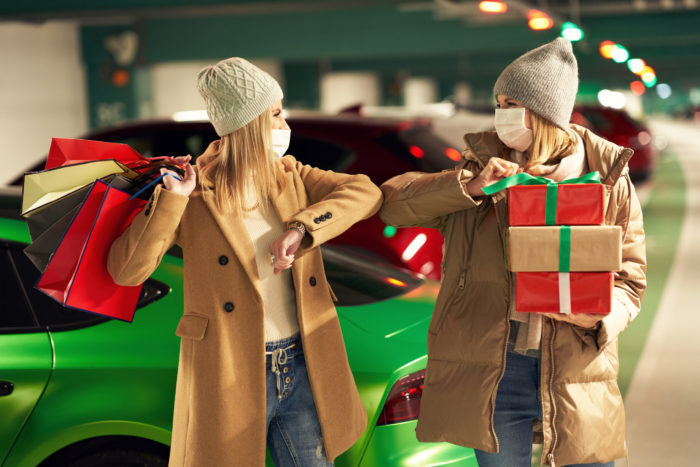 Two women with shopping bags in masks in underground parking lot