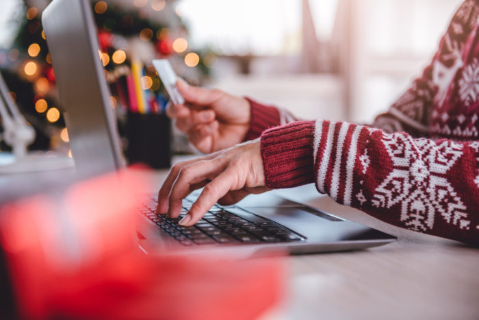 Women wearing red sweater shopping online and using credit card at home office